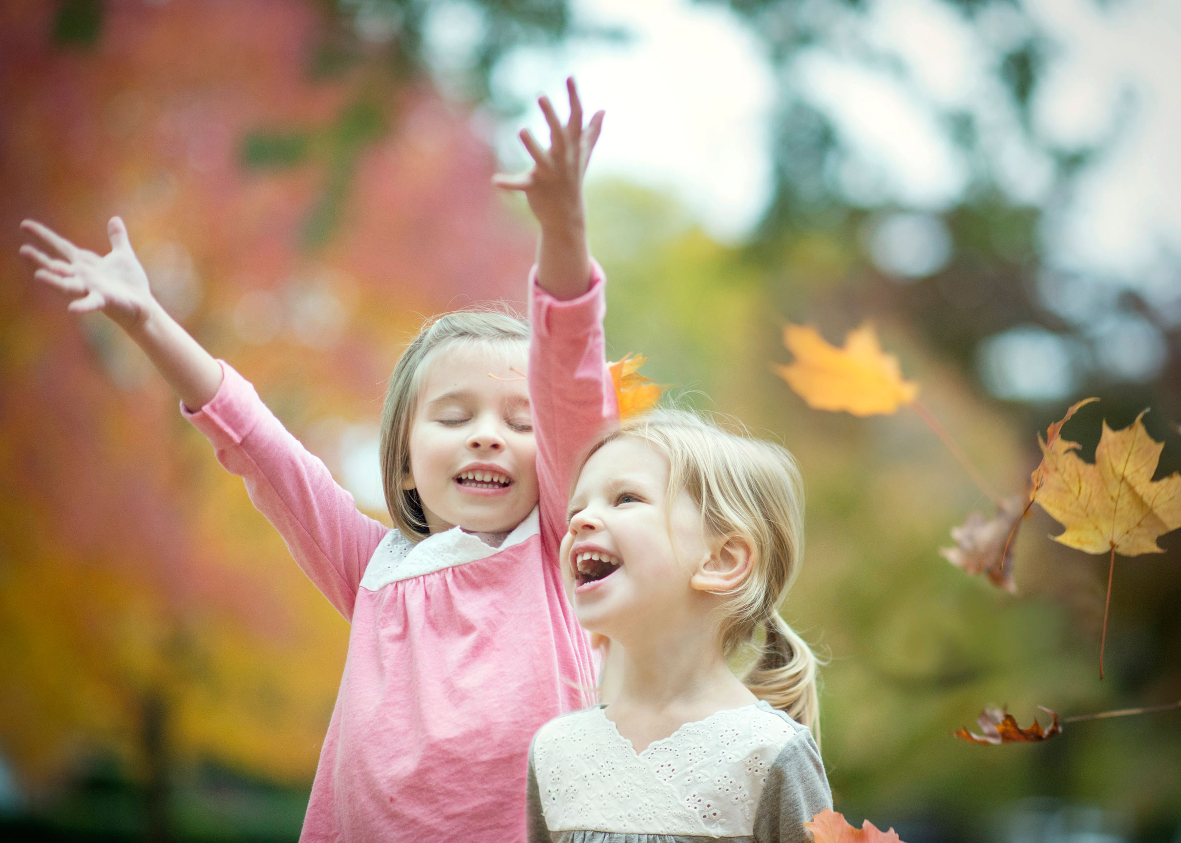 sisters throwing autumn leaves