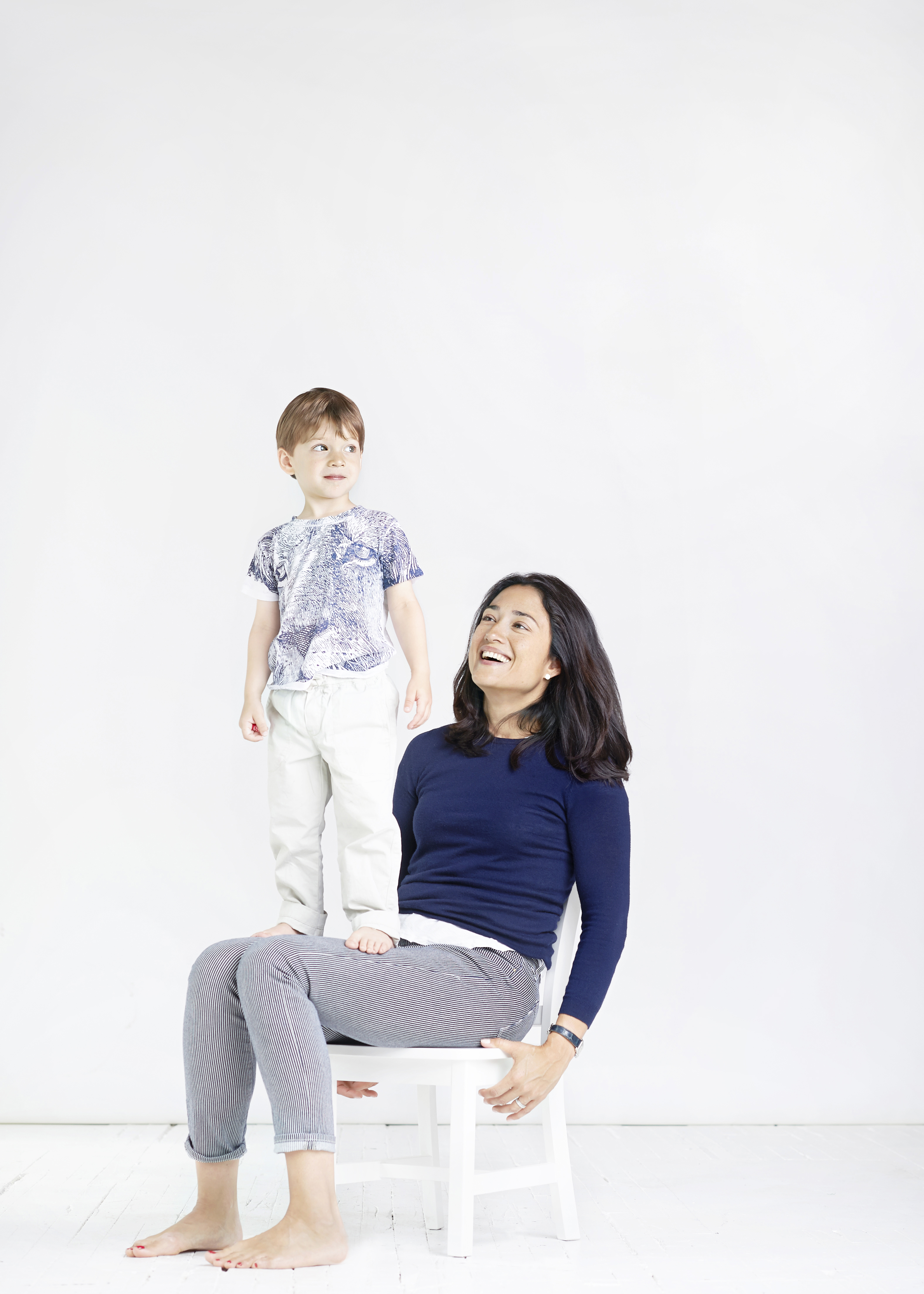 boy standing on moms legs in studio
