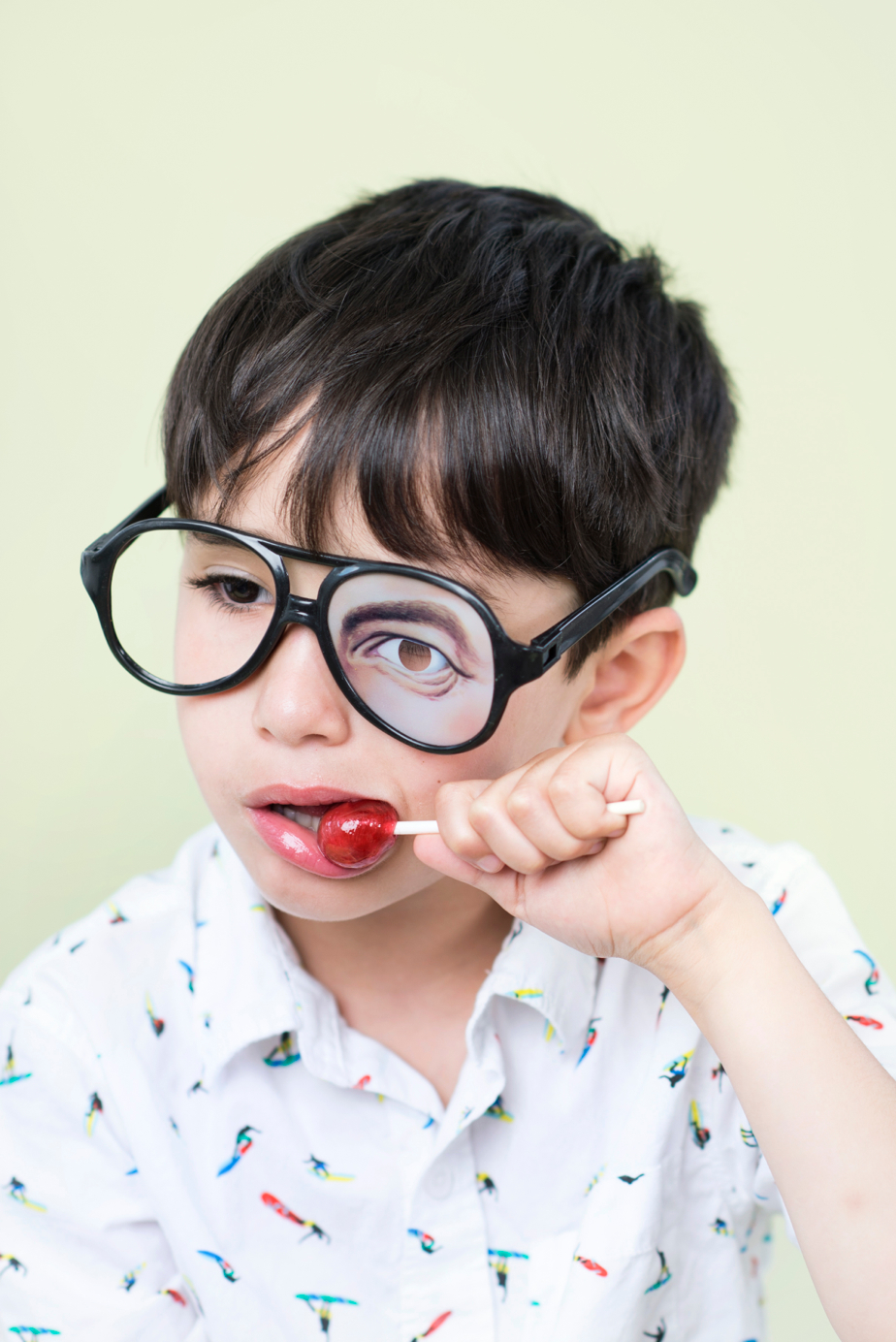 boy with silly glasses eating lollipop