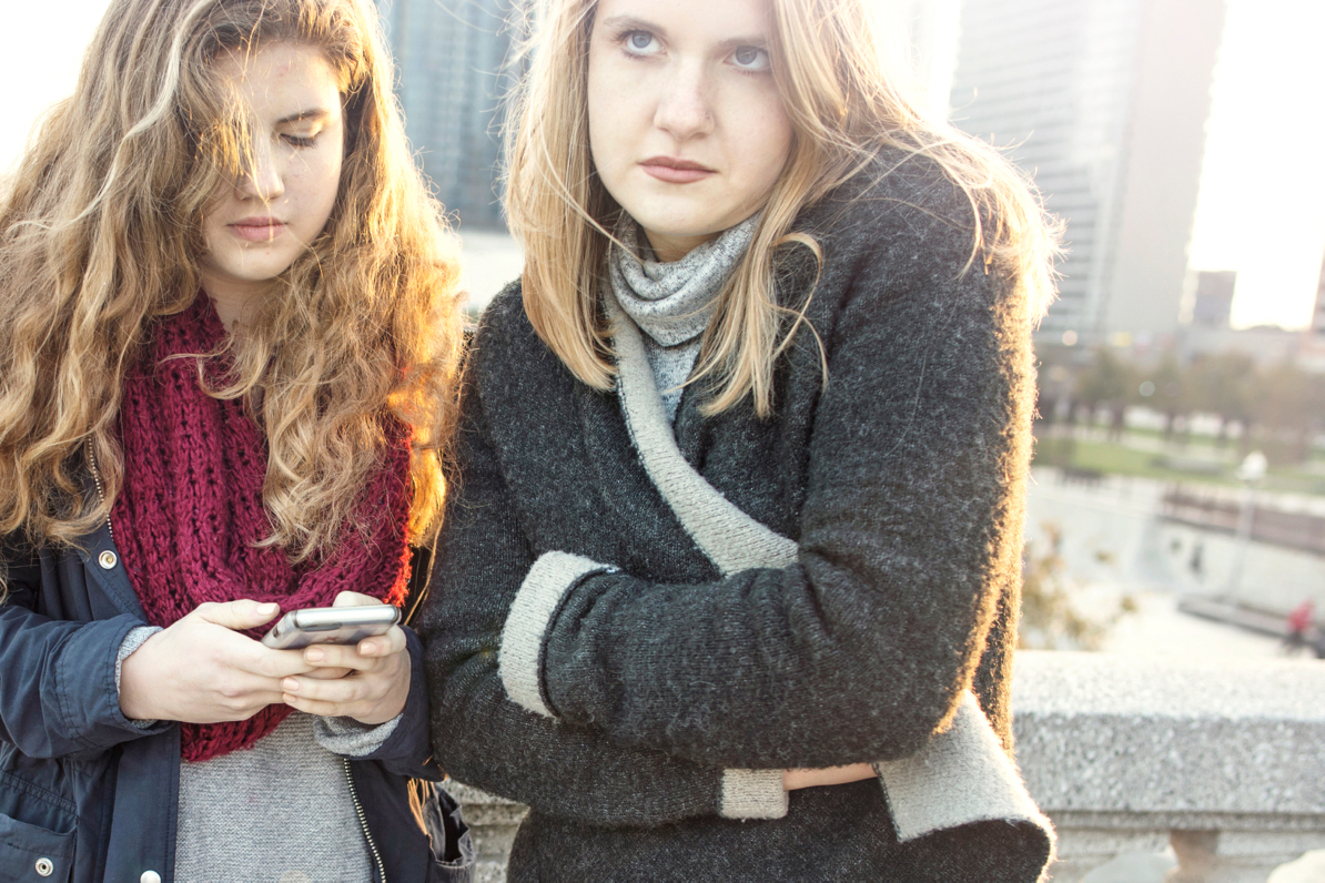 grumpy sisters in sweaters with cell phone