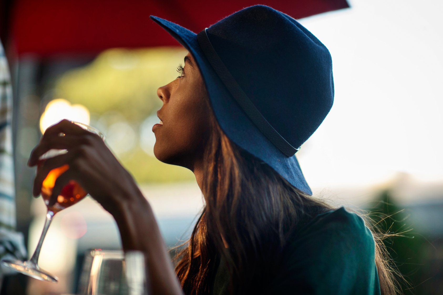 girl in silhouette drinking wine with blue fedora